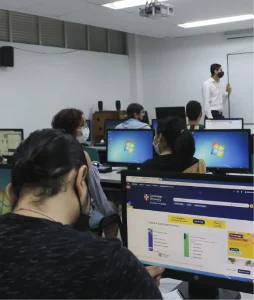 Fotografía en plano general donde se ven a los estudiantes trabajando en sus respectivos computadores
