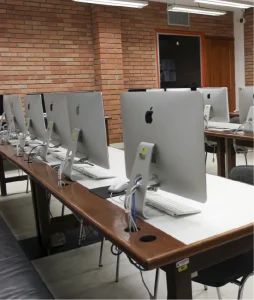 Fotografía de la sala donde se aprecian escritorios, cada uno equipado con un computador