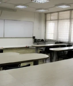 Foto de la sala vacía donde se ven los escritorios y el tablero de fondo
