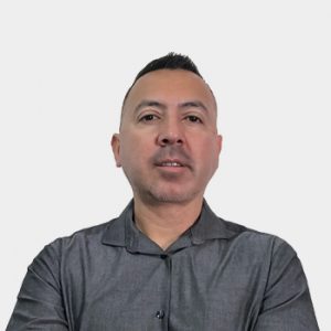 La foto fue tomada en primer plano, fondo blanco y el profesor Jhon Jairo Briceño está situado en el centro.
