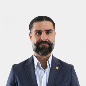 La foto fue tomada en primer plano, fondo blanco y el profesor Carlos Muvdi Nova está situado en el centro.