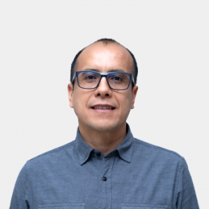 La foto fue tomada en primer plano, fondo blanco y el profesor Carlos Andres Cardenas está situado en el centro.