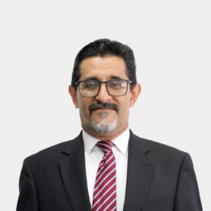 La foto fue tomada en primer plano, fondo blanco y el profesor Emiliano Ariza León está situado en el centro.