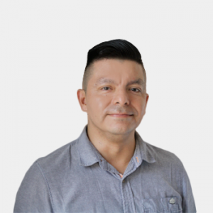 La foto fue tomada en primer plano, fondo blanco y el profesor Milton Dionisio Lozano está situado en el centro.